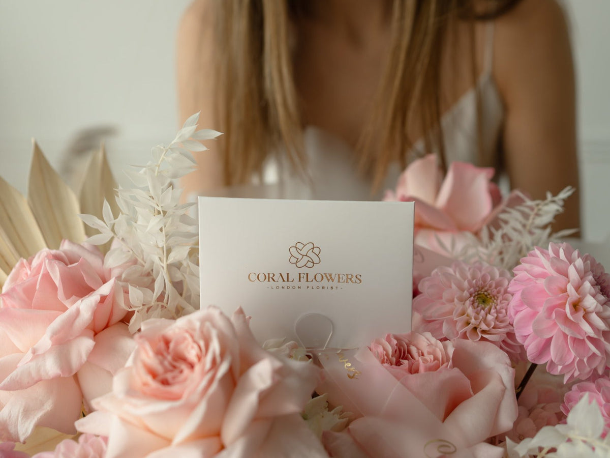 Woman receiving a pink rose and dahlia bouquet with a Coral Flowers London card